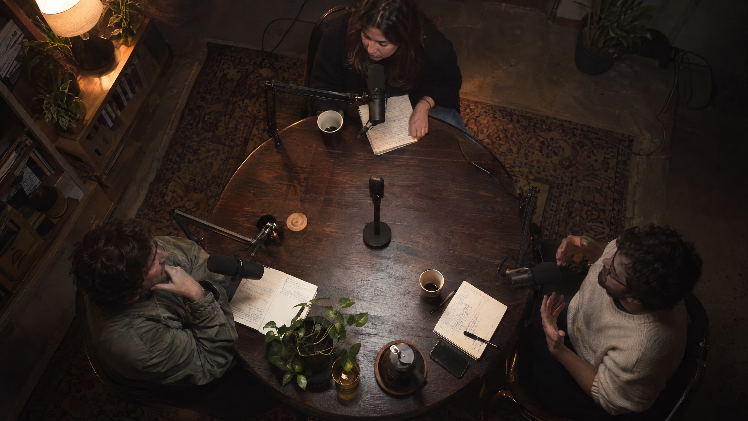 Top-down view of a round podcast table with three people and the 360° camera in the centre.